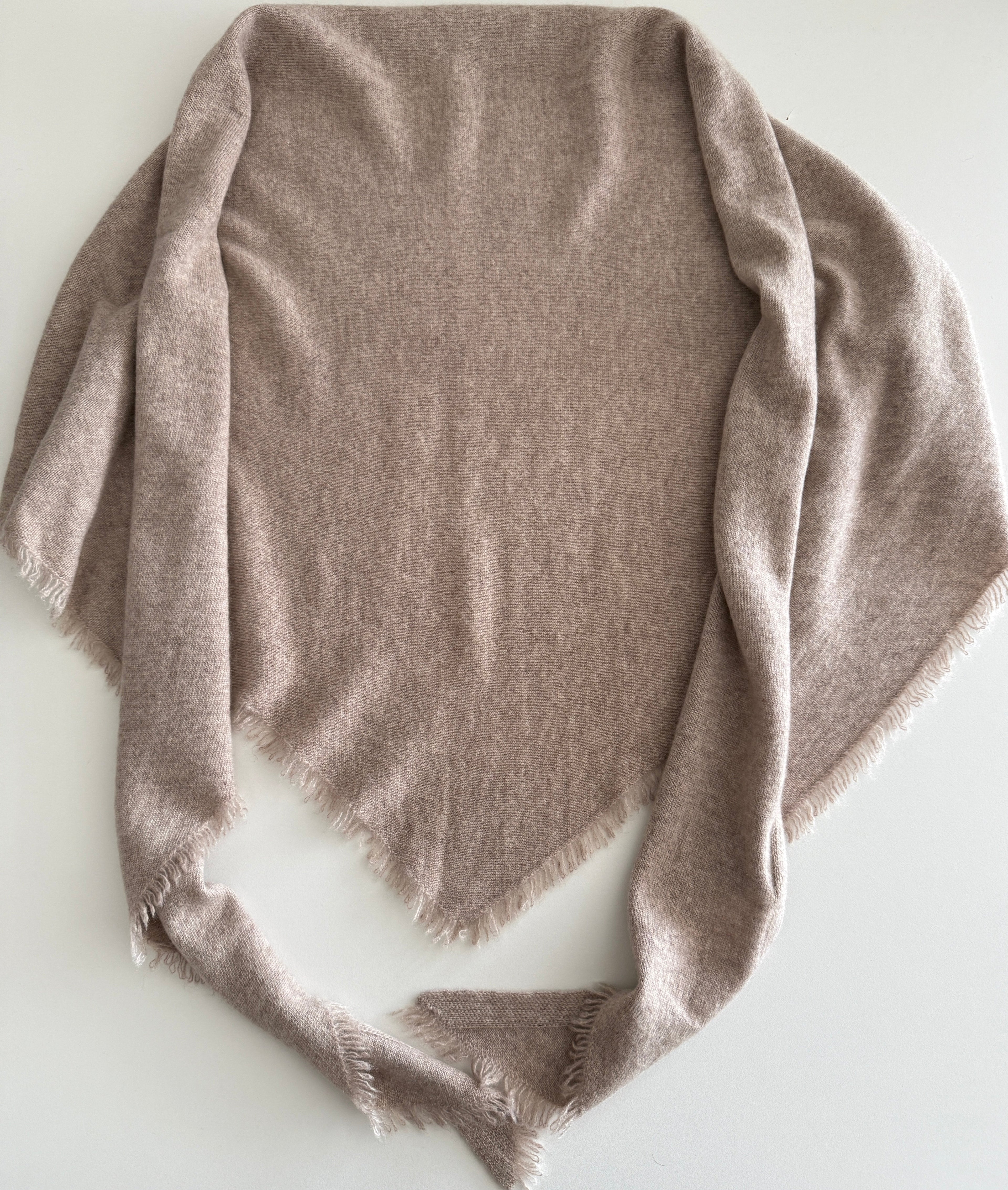 Folded beige bandanna on a white surface